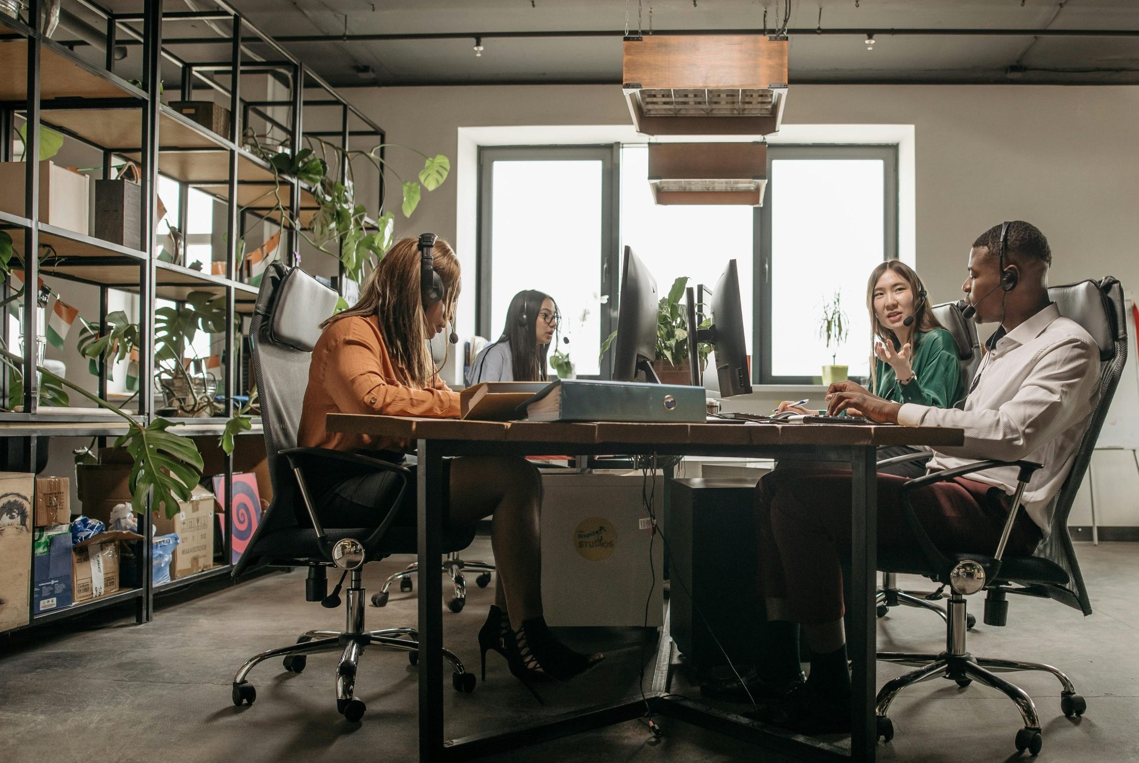 A diverse call center team working on computers with headsets in a modern office setting.